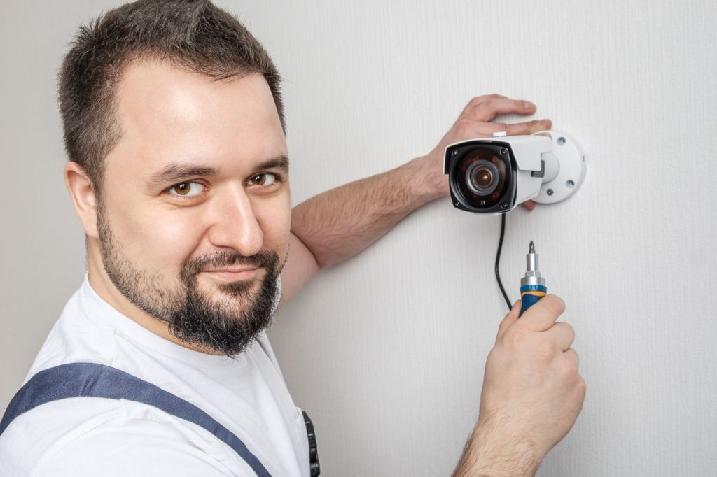 Professional CCTV technician working. Man installing surveillance ip camera for home security